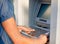 Woman using ATM holding card and pressing the PIN security number on the keyboard automatic teller machine