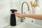 Woman using automatic soap dispenser in kitchen