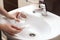 Woman using baking soda to unclog sink drain in bathroom, closeup