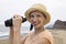 Woman using binoculars at beach (portrait)