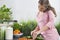 Woman using cell phone while cutting cucumber at kitchen counter