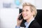 Woman Using Cordless Phone While Looking Up In Office