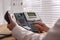 Woman using desktop telephone at wooden table in office, closeup. Hotline service