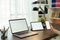 Woman using digital laptop and tablet with smartphone on the table in house. Blank screen for advertising.