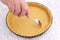 Woman using fork to holes in an uncooked pie crust