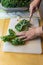 Woman using a knife to cut the rib from the center of a kale lea