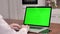 Woman using laptop computer with laptop green screen, 4K shot. Technology, chroma key, template, mockup and entertainment concept