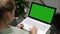 Woman using laptop computer on a outdoor terrace, blank green screen copy space