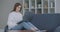 Woman using laptop on couch at home. Thoughtful young woman sitting with computer on couch, looking outside, concentrate