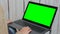 Woman using laptop with green screen