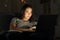 Woman using a laptop in the night on a couch