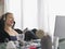 Woman using laptop wearing headset sitting at desk