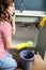 Woman using mobile phone while cleaning kitchen sink