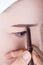 Woman using pencil makeup eyebrow