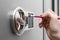 Woman using pencil to enter code on keypad of safe, closeup