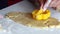 A woman using a plastic mold forms cookies from rolled dough. Close-up shot