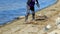 A woman using a rake to clean debris on the beach along the lake shore