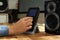 Woman using remote to control audio speakers at wooden table indoors, closeup