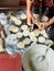 A woman using a rolling pin and a glass prepares a dough for making dumplings