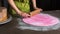 Woman using rolling pin preparing pink fondant for cake decorating