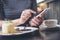 A woman using smart phone with cake and coffee cup on wooden table