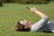 Woman using a smart phone resting on the grass in a park