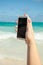 Woman using smart phone for taking photo on a beach