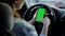 A woman using a smartphone with a green screen in her hand driving a car. Chroma key.