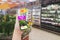 Woman using smartphone to check prices for merchandise and products on blurred supermarket shelves,Augmented Reality Or AR in