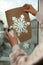 Woman using snow spray for decorating window with snowflakes at home, closeup