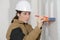 Woman using spirit level and pencil marking wall