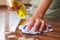 Woman Using Spray Cleaner On Wooden Surface