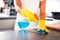 Woman Using Spray Polish To Clean Kitchen Surface