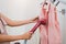 Woman using steaming iron to ironing fashion shirt in laundry room. Girl doing stream vapor iron for press clothes in hand.