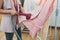 Woman using steaming iron to ironing fashion shirt in laundry room. Girl doing stream vapor iron for press clothes in hand.