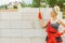 Woman using string as level in wall construction