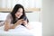 Woman using telephone on bed in bedroom