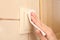 Woman using tissue paper to switch on light indoors, closeup