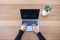 A woman using and typing on laptop with cactus pot on wooden table background