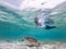 Woman on vacations wearing snokeling mask swimming with sea turtle in turquoise blue water of Gili islands, Indonesia