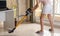 Woman vacuuming the living room with a cordless vacuum cleaner