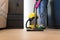 Woman vacuuming the parquet floor in the room with professional vacuum cleaner. Cleaning company employee cleans the house.