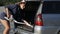 Woman vacuums car trunk with vacuum cleaner removing dirt and dust from car trunk outdoors at sunset