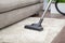 A woman vacuums a gray carpet with a vacuum cleaner. Cleaning and cleanliness concept