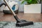 A woman vacuums a gray carpet with a vacuum cleaner. Cleaning and cleanliness concept