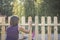 Woman varnishing a wooden picket fence