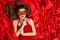 Woman in Venetian Mask Lying on Red Silk Fabric Background, Fashion Model Finger on Lips