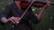 Woman violinist plays the violin on meadow at dusk. Closeup.