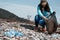 Woman volunteer helps clean the beach of garbage. Earth day and environmental improvement concept. Stone coast on the background