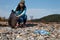 Woman volunteer helps clean the beach of plastic garbage. Earth day and environmental improvement concept. Stone coast on the